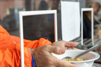 Zwei Hände nehmen einen Teller Suppe entgegen