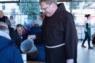 Franziskanerbruder schenkt bedürftigen Menschen Tee ein.