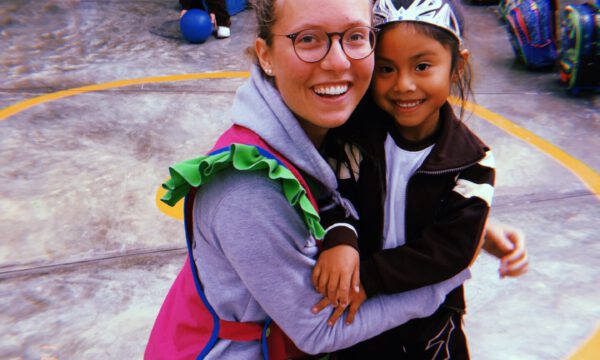 Freiwillige umarmt peruanisches Kind im Colegio San Francisco de Asís
