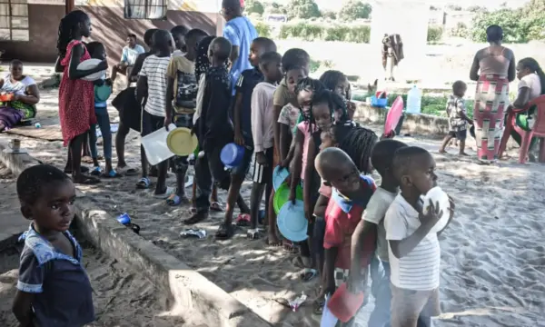 Kinder mit leeren Tellern in der Hand stehen Schlage für eine Essensausgabe nach den Überschwemmungen in Mosambik