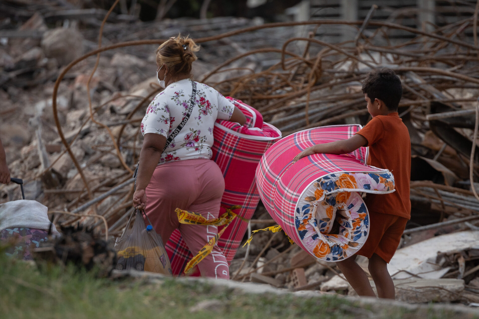 Eine Frau und ein Kind tragen Matratzen und persönliche Gegenstände durch die Trümmer nach dem Erdbeben in Venezuela. Franziskaner Helfen unterstützt Familien vor Ort mit humanitärer Nothilfe.