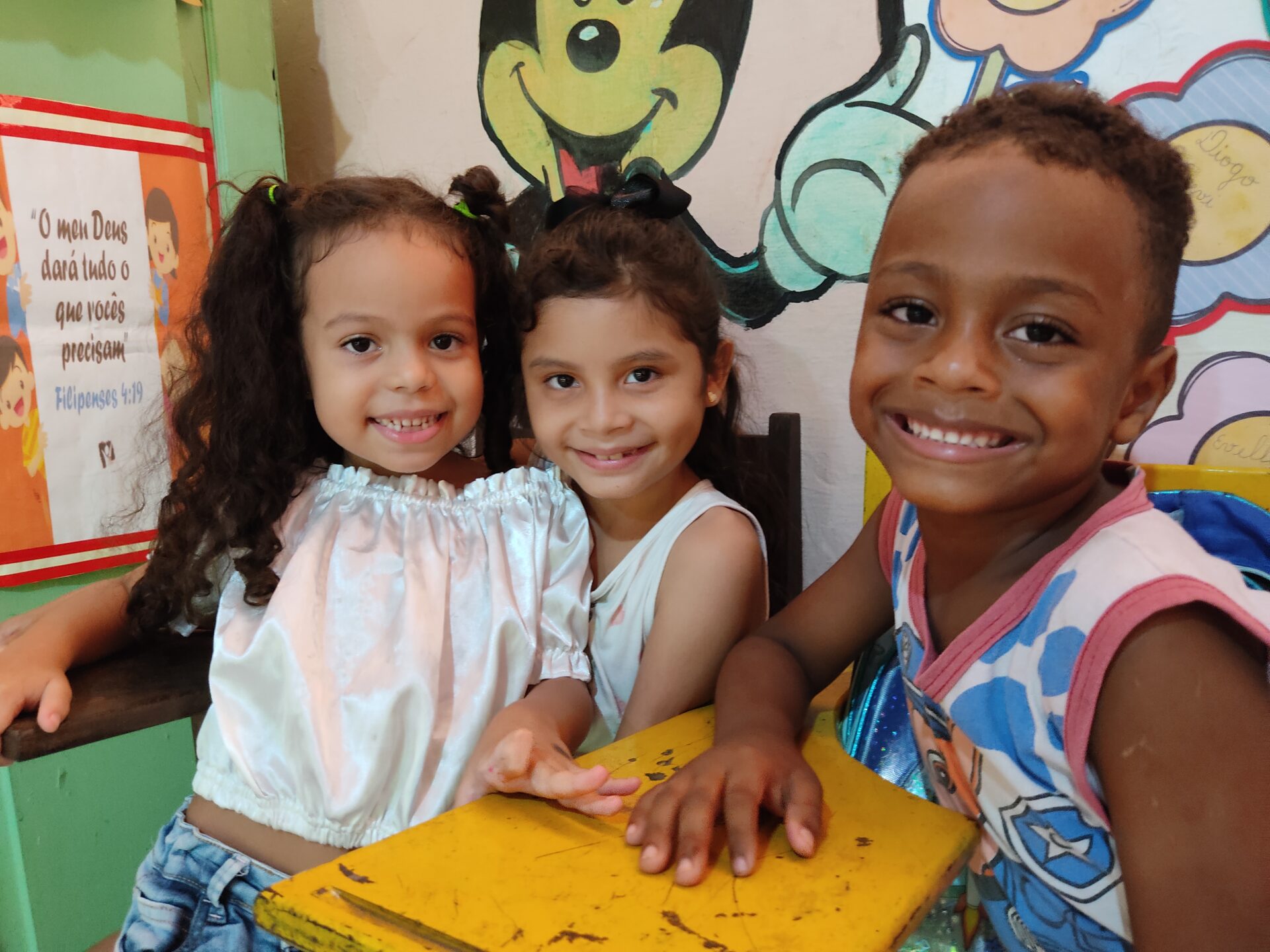 Drei Kinder lächeln gemeinsam in einer Betreuungseinrichtung von Franziskaner Helfen in Brasilien in die Kamera.