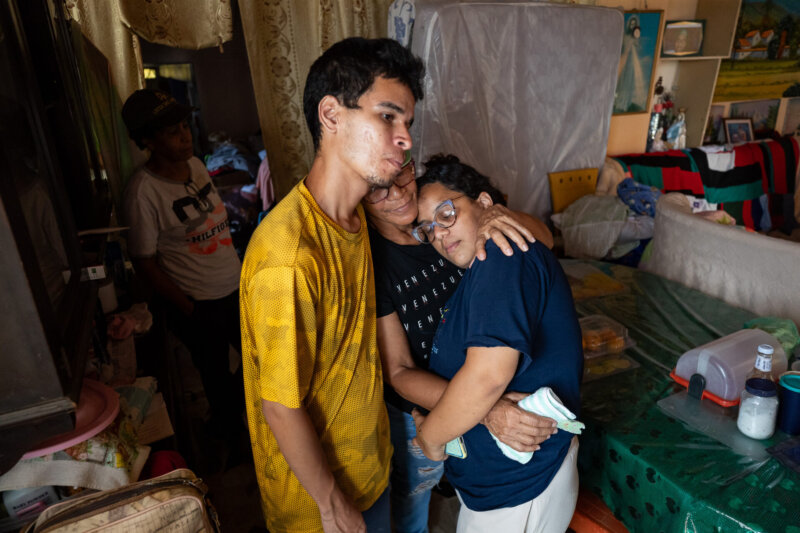 Eine Familie hält sich nach dem Erdbeben in Venezuela tröstend im Arm. Im Hintergrund sind die Schäden in ihrem Zuhause sichtbar.