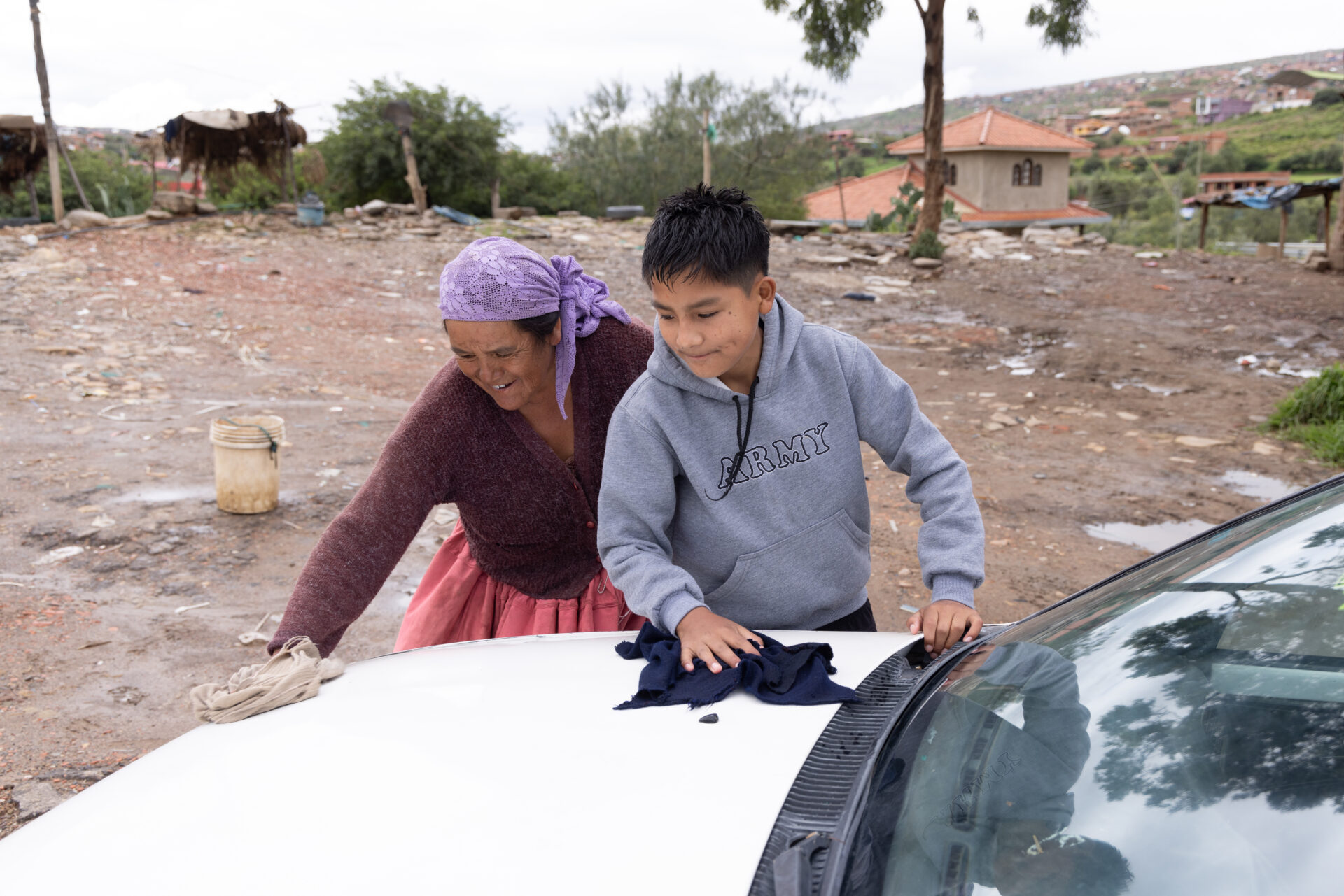 Ein Junge und eine Frau reinigen gemeinsam ein Auto bei einem sozialen Projekt in Bolivien.