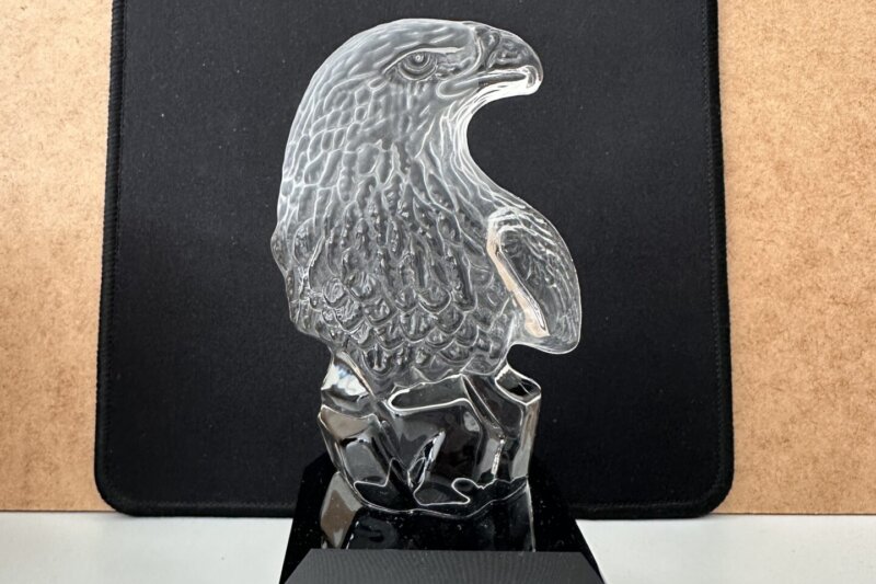 Gläserne Adler-Trophäe auf schwarzem Sockel mit der Aufschrift „Griffix Film Awards – Best Ad – Franziskaner Helfen – 2026“.