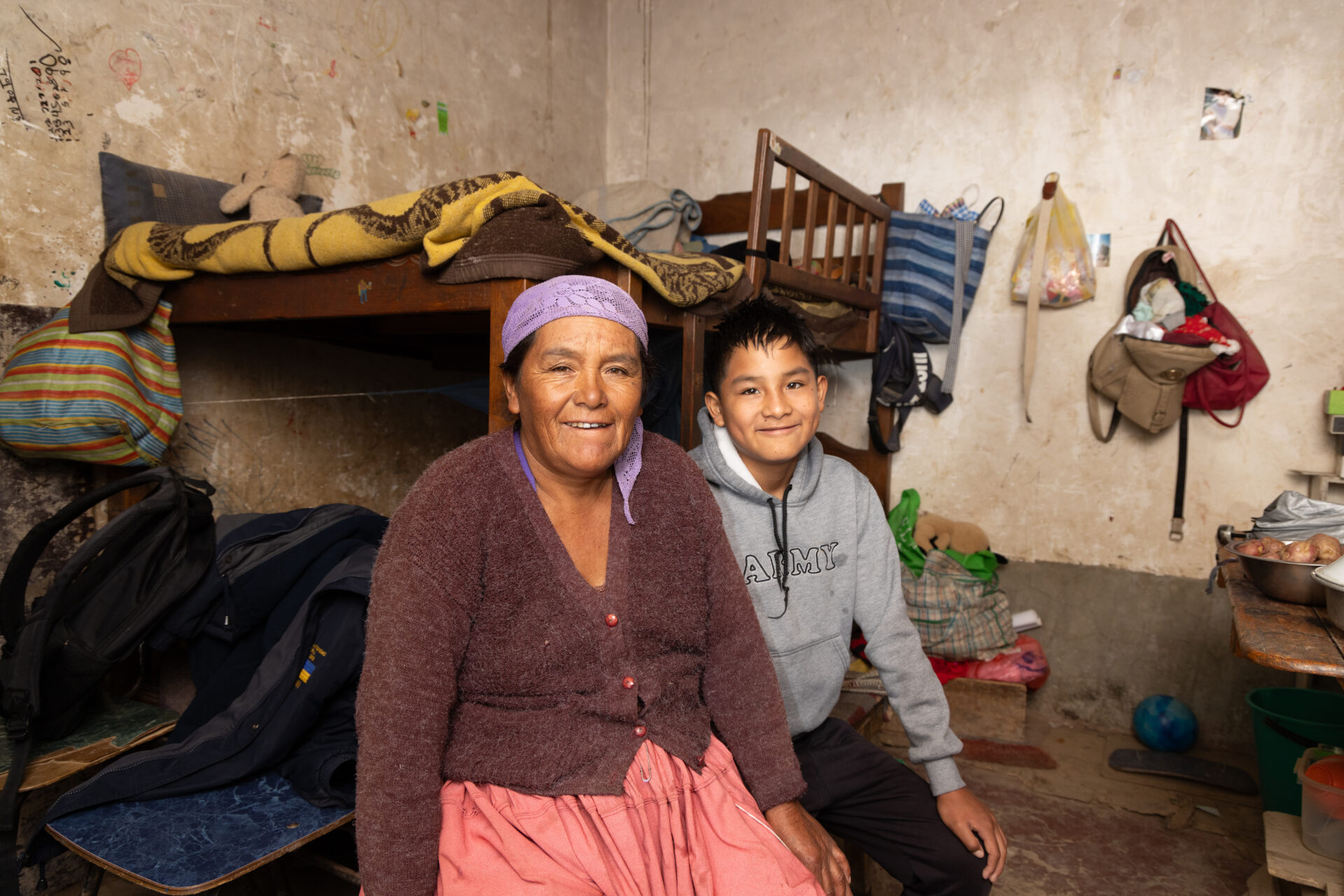 Jhonatan sitzt gemeinsam mit seiner Mutter in ihrem Zuhause in Cochabamba, Bolivien.