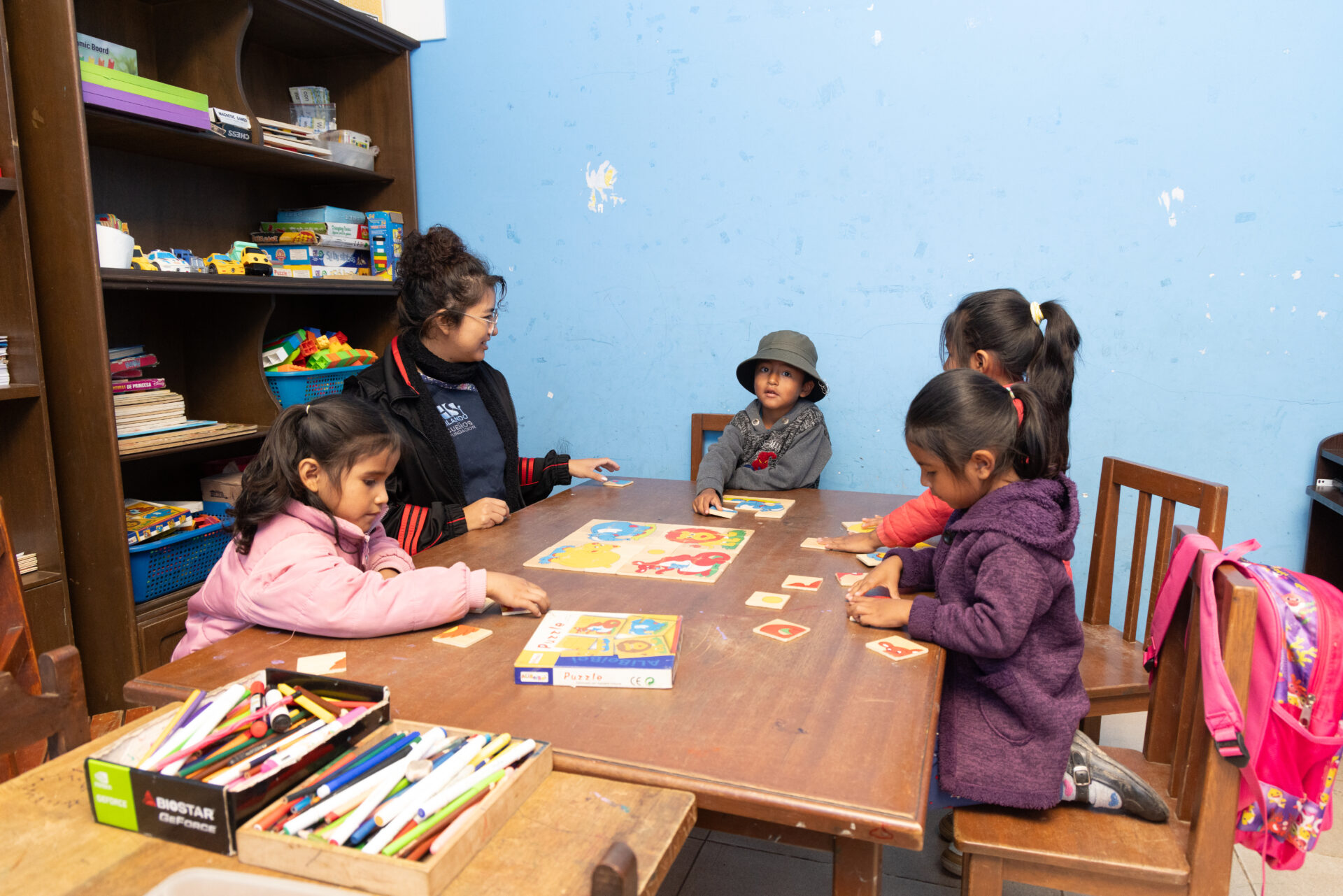 Eine Betreuerin spielt mit mehreren kleinen Kindern ein Lernspiel in einer Tagesstätte der Franziskaner in Cochabamba.