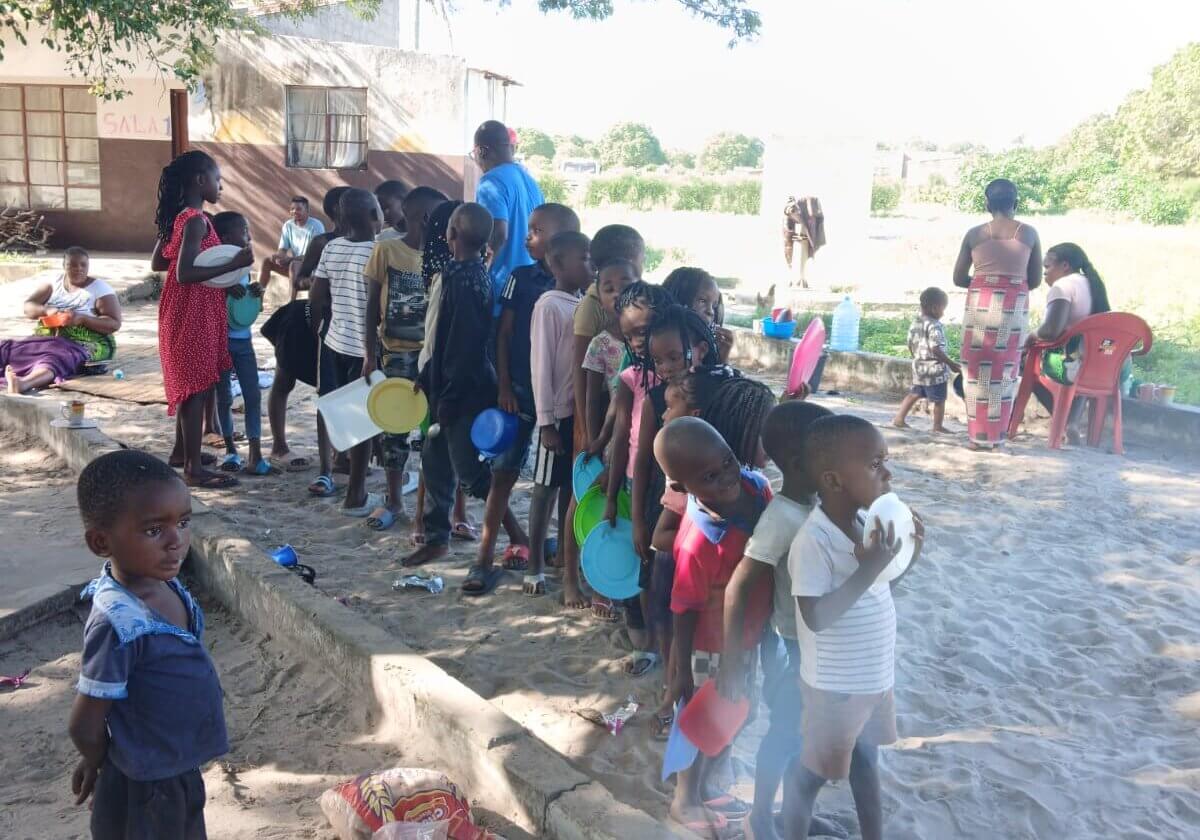 Kinder mit leeren Tellern in der Hand stehen Schlage für eine Essensausgabe nach den Überschwemmungen in Mosambik