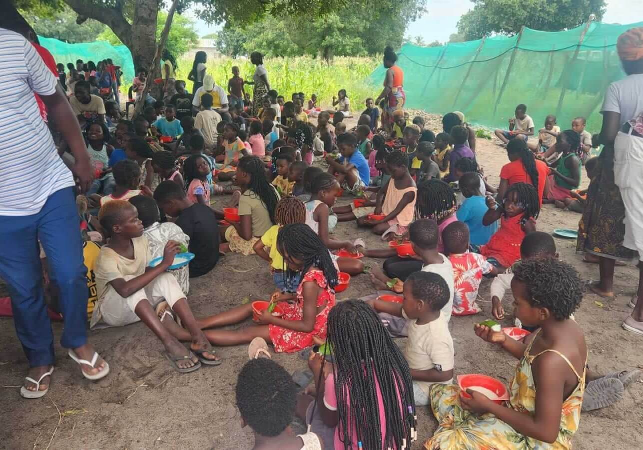 Kinder sitzen nach den Überschwemmungen in Mosambik auf dem Boden und essen.