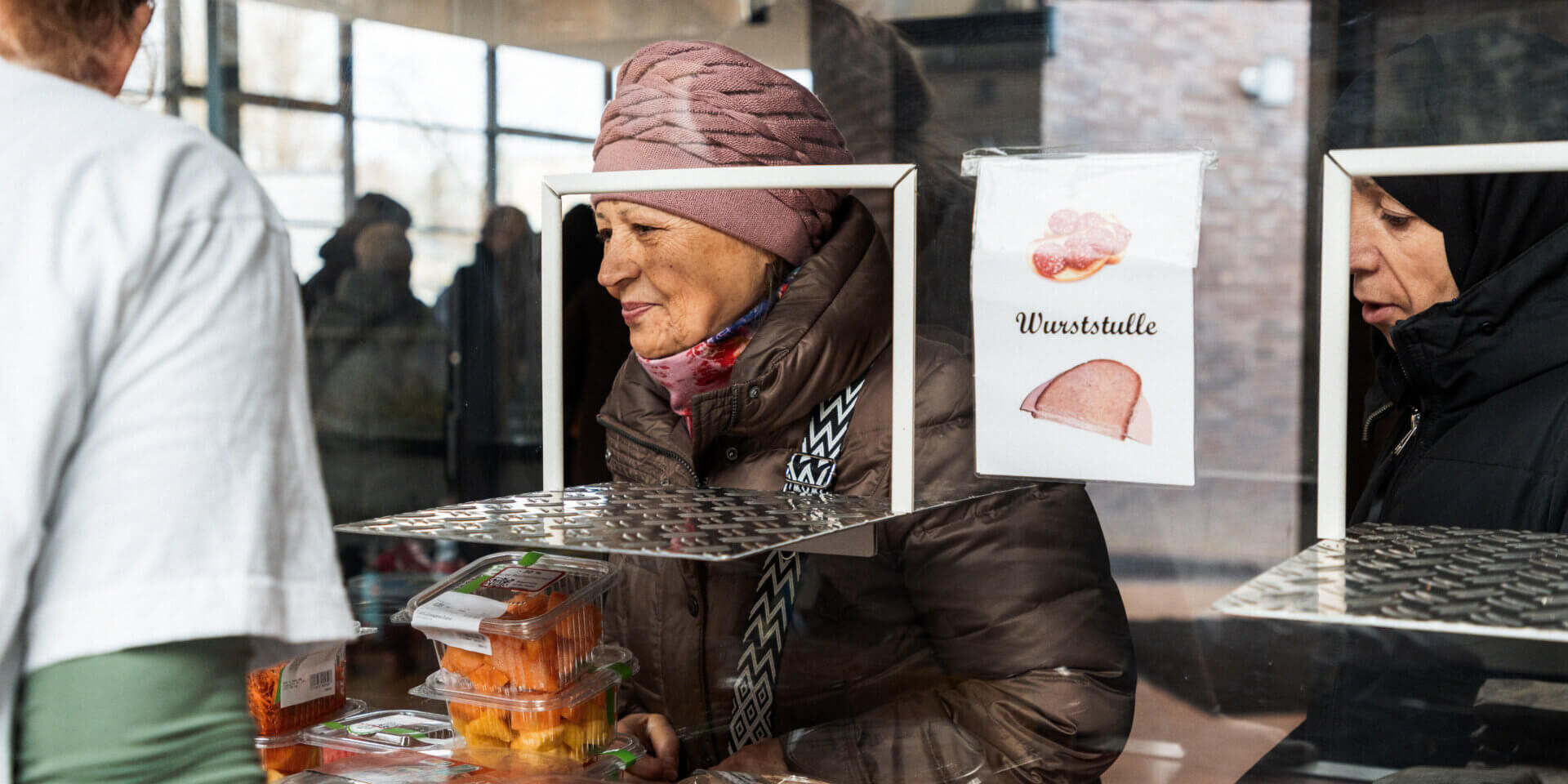 Frau wählt Mahlzeit an der Essensausgabe der franziskanischen Suppenküche aus.