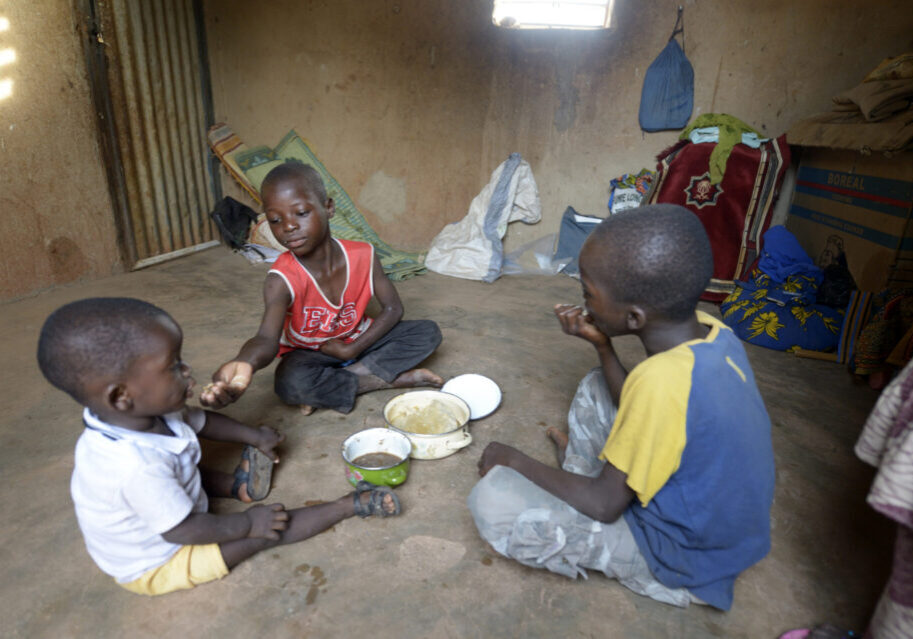 Die Jungen Arnna (1 Jahr und 3 Monate), Fatao (10, blau), Kader (9, rot) beim Frühstück, Dorf Toeghin, Provinz Oubritenga, Region Plateau Central, Burkina Faso