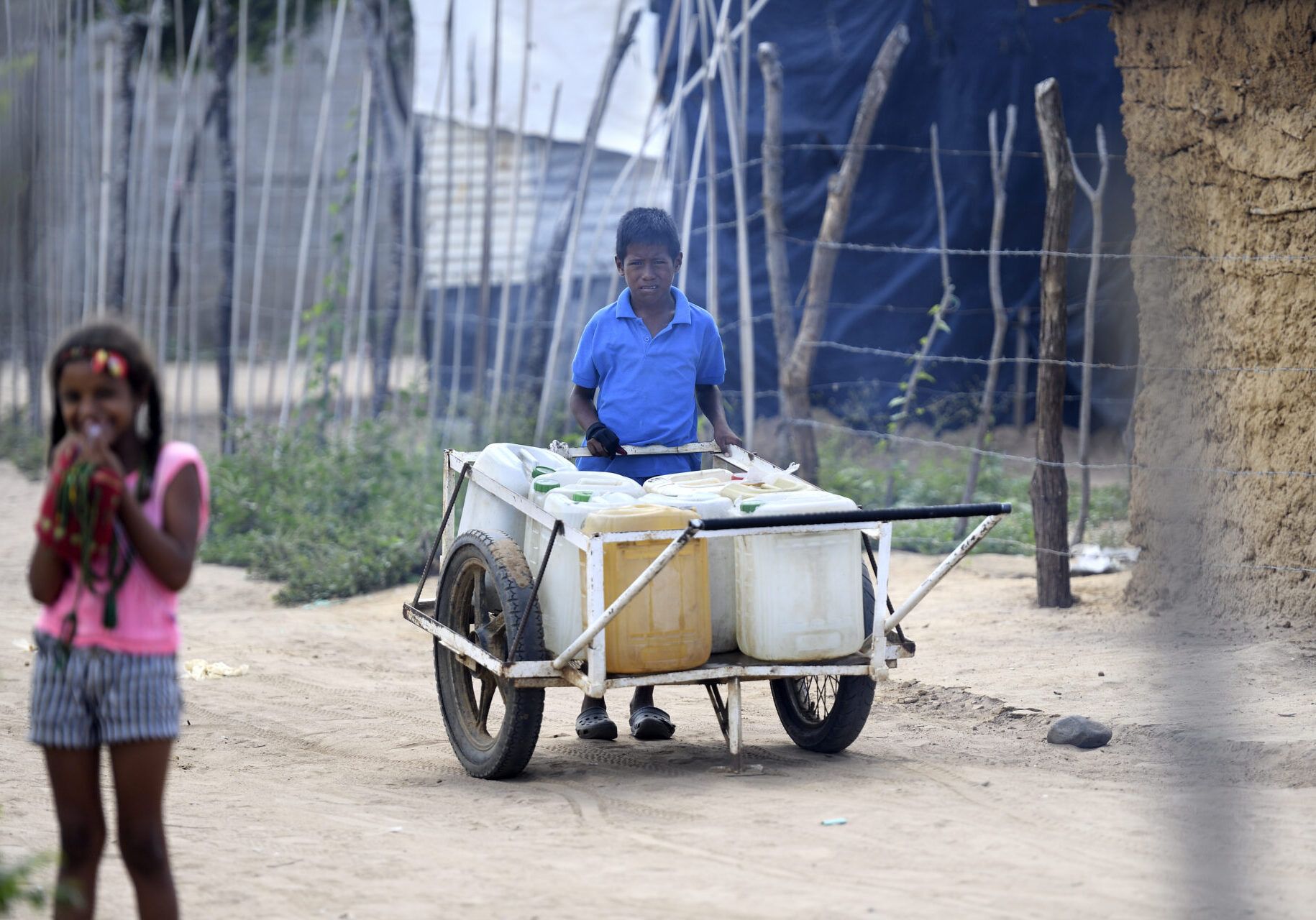 Straßenszene (Junge verkauft Trinkwasser in Kanistern) mit Migranten aus Venezuela im Armenviertel Villa del Sur, Riohacha, Bundesstat La Guajira, Kolumbien