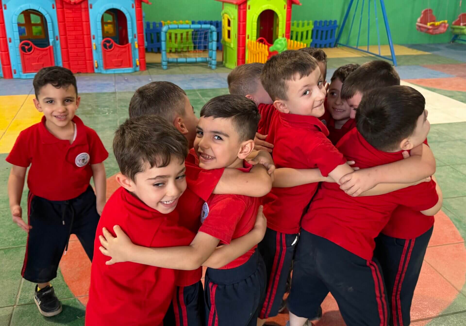 Kinder im Kindergarten von Franziskaner Helfen im Irak spielen und umarmen sich in einem sicheren und geschützten Umfeld.